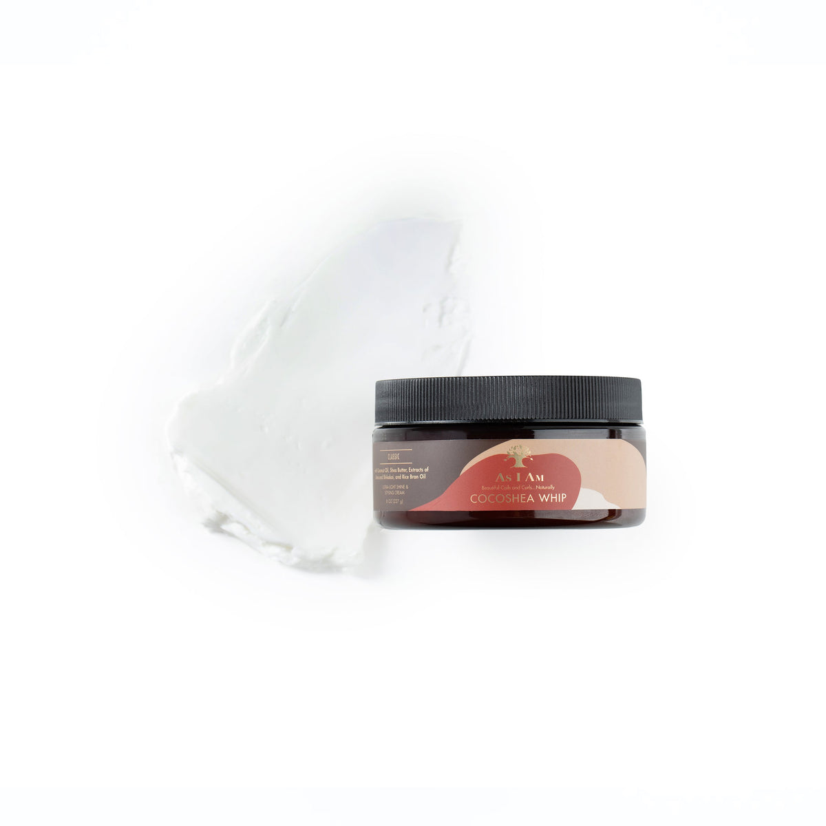 A brown plastic tin with a label contains As I Am CocoShea Whip. The product is a leave-in conditioner for curly hair and has a creamy consistency. The jar is on a white background and there is a bit of the product smeared on the side.