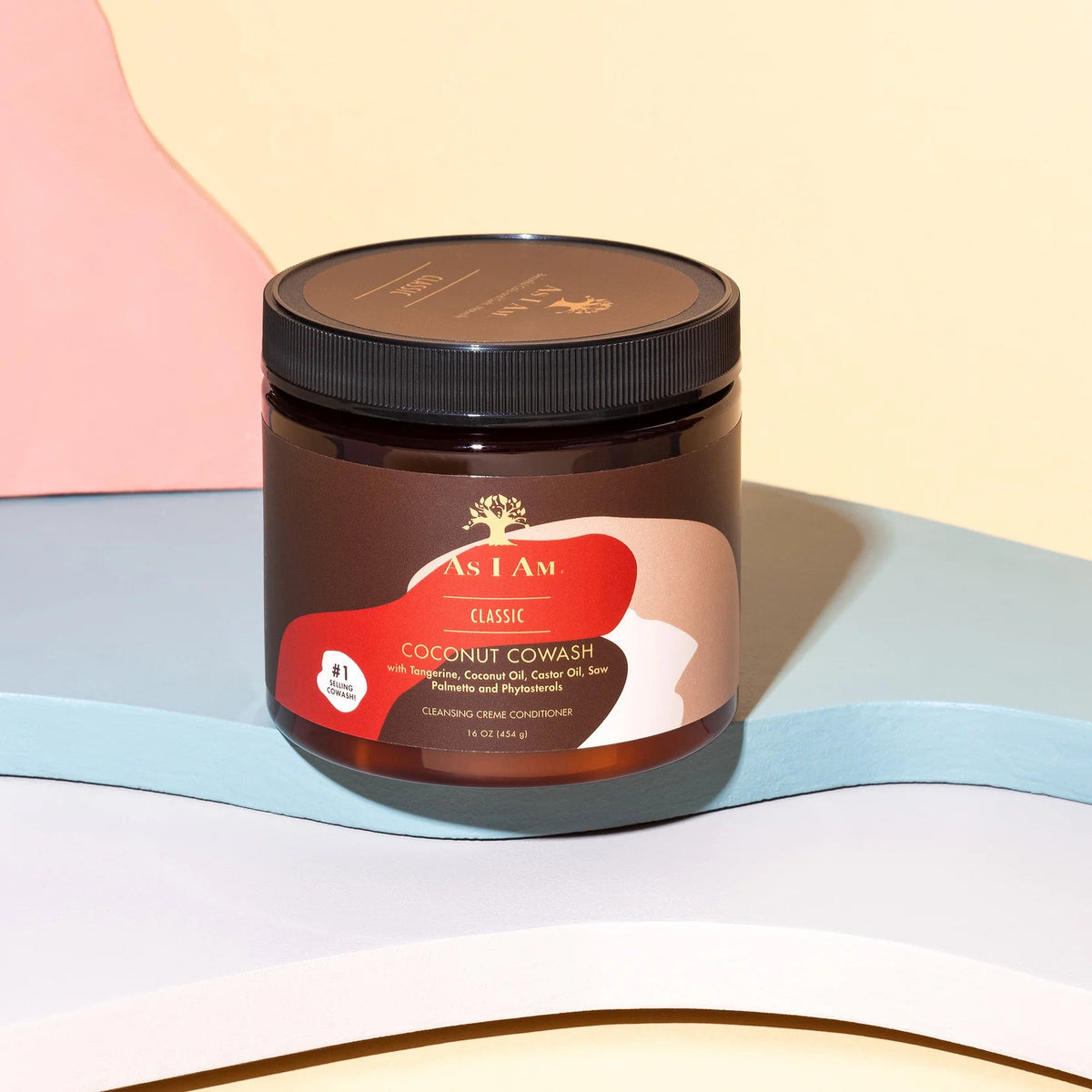 A brown tin with a label contains As I Am Classic Coconut Co-Wash. The product is designed to clean and moisturize curly hair. The label has a picture of a coconut and mentions ingredients such as coconut oil and castor oil.