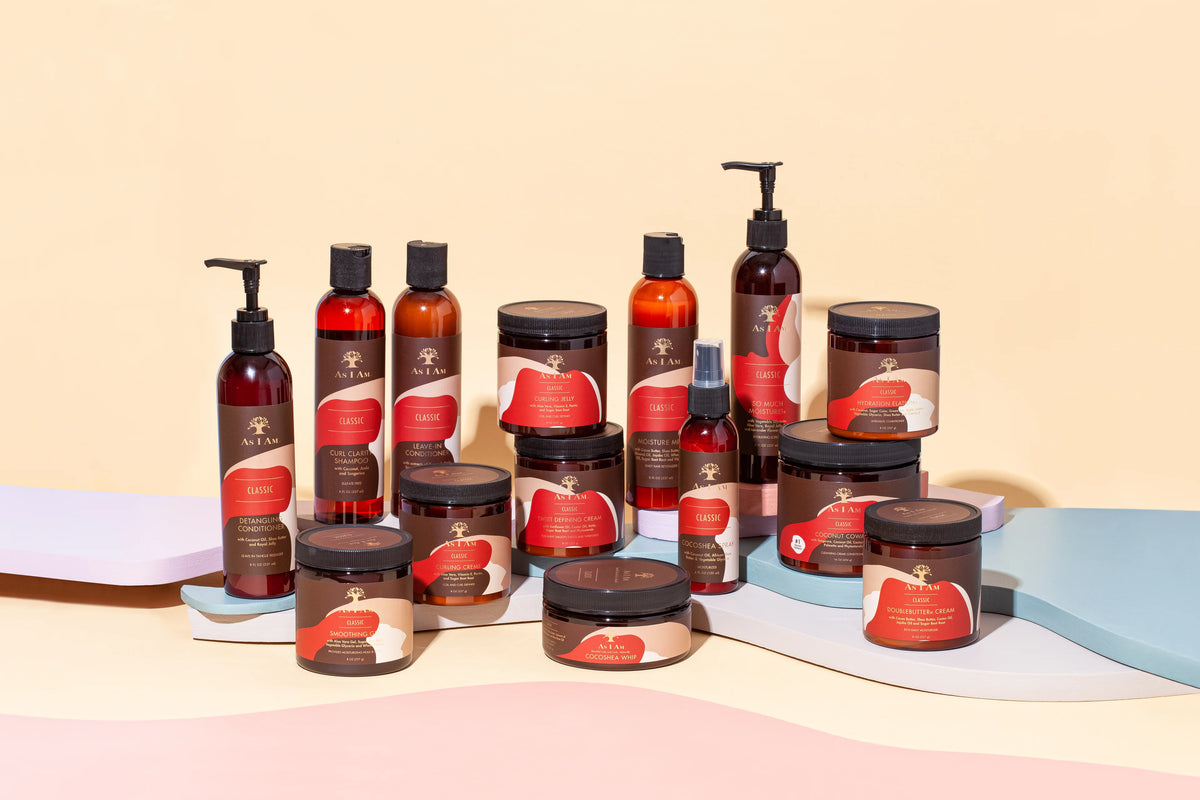 A selection of hair care products from As I Am presented on a colorful background. The products include bottles, jars and spray bottles in various sizes and shapes, all with the distinctive As I Am design.