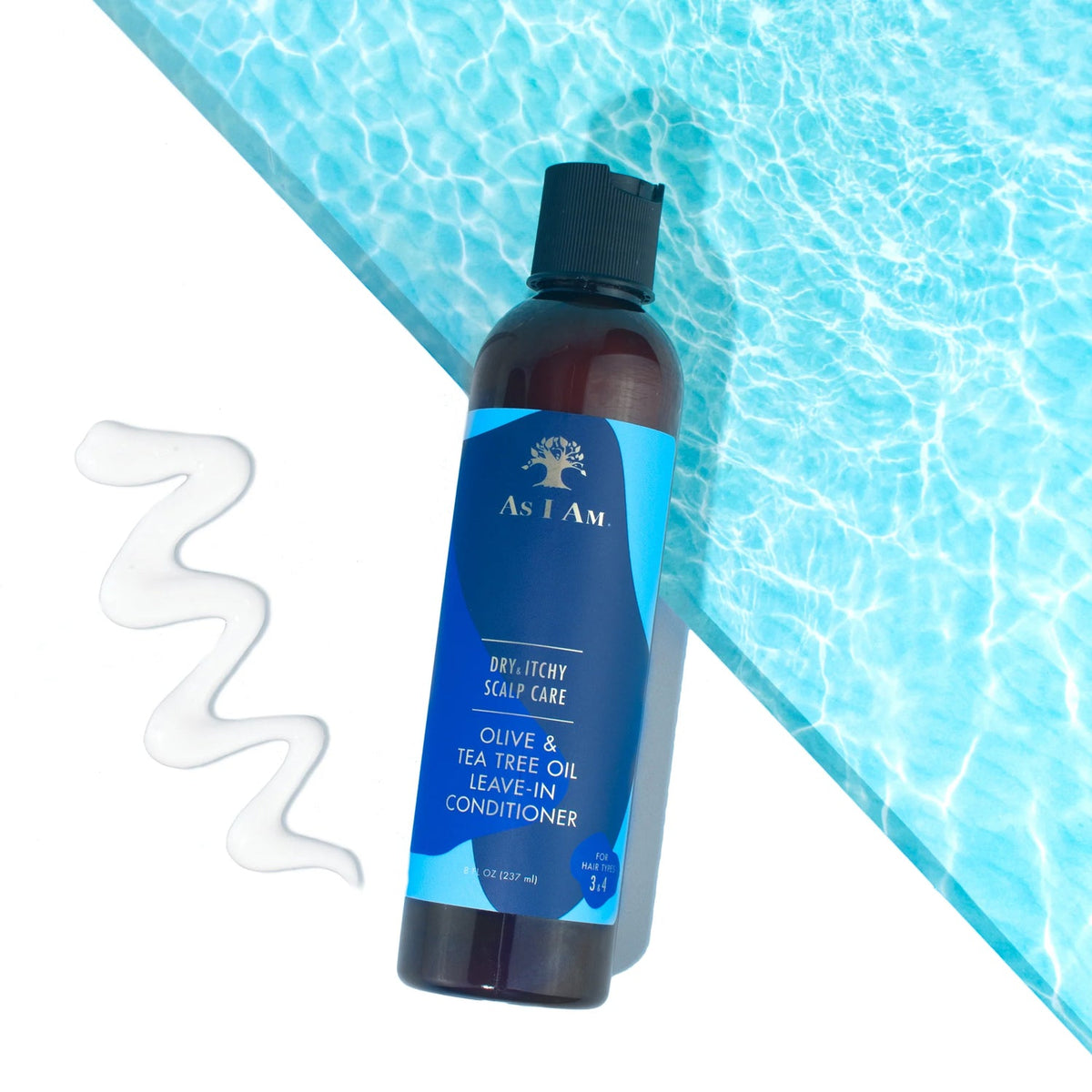 A bottle of As I Am Dry & Itchy Scalp Care Leave-in Conditioner stands in front of a background reminiscent of water. A dab of the white conditioner is placed next to the bottle.