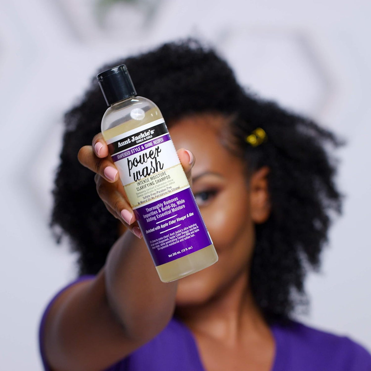 Woman holding a bottle of Aunt Jackie's Power Wash Intense Moisture Clarifying Shampoo.