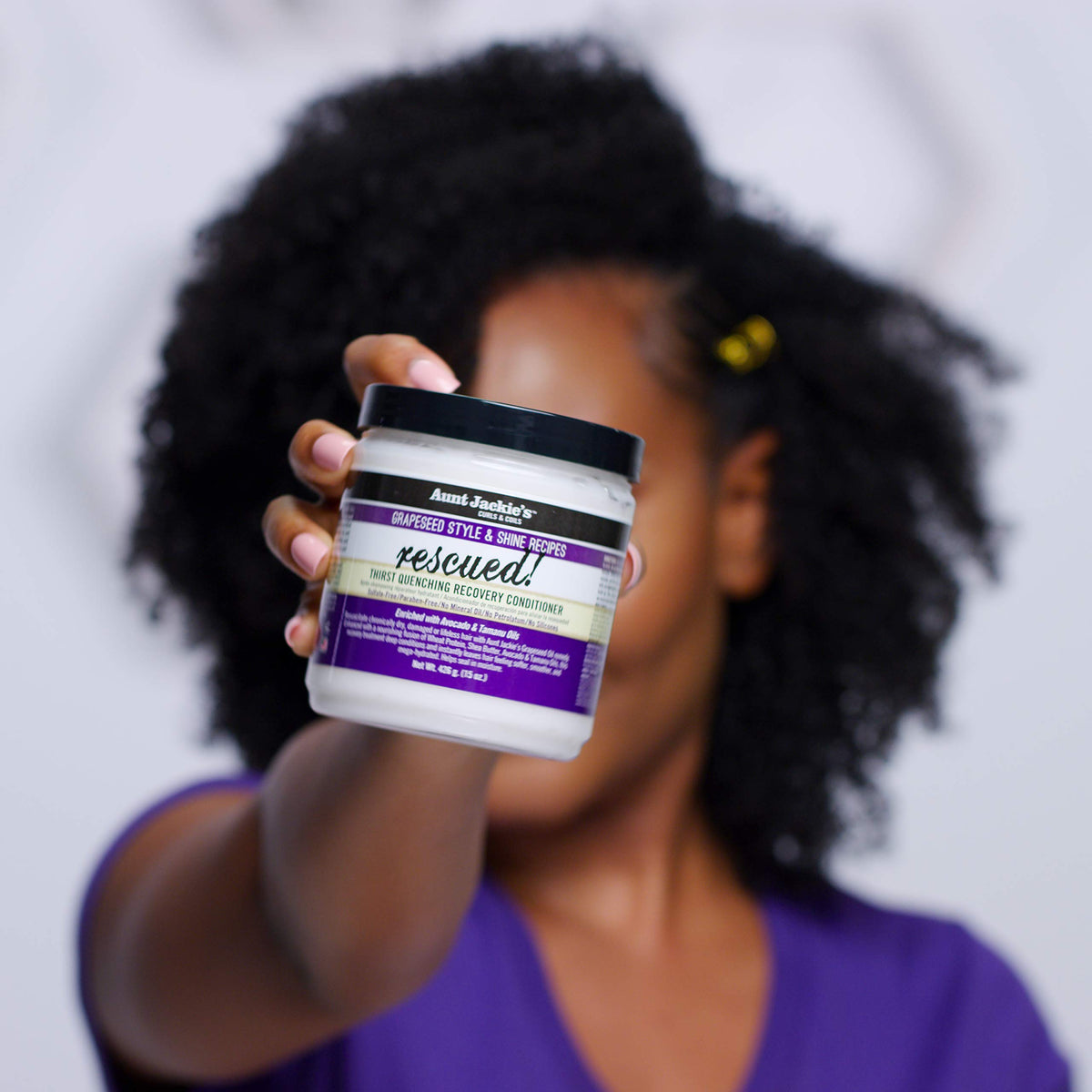 Aunt Jackie's Rescued Thirst Quenching Recovery Conditioner. A woman holds the jar of hair treatment containing grape seed, avocado and tamanu oil for dry hair.