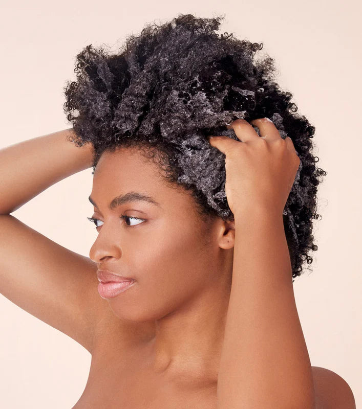 Woman using the product Not Your Mothers Tahitian Gardenia Flower Mango Butter Shampoo.