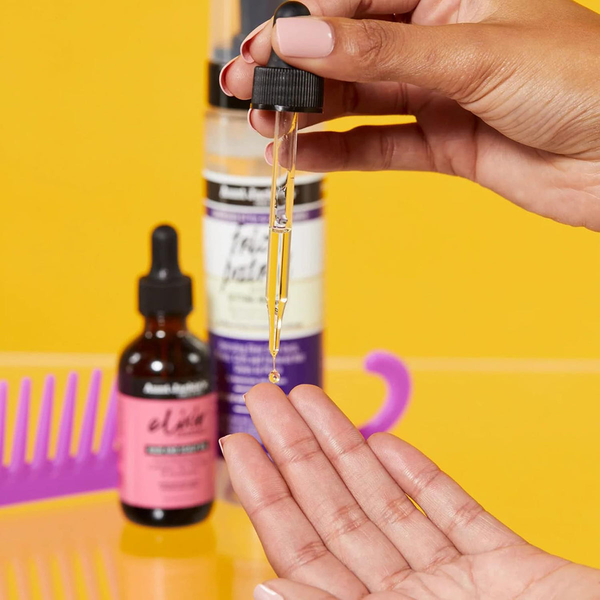 Close-up of Aunt Jackie's Elixir Hair Oil being dripped from the dropper into a hand.