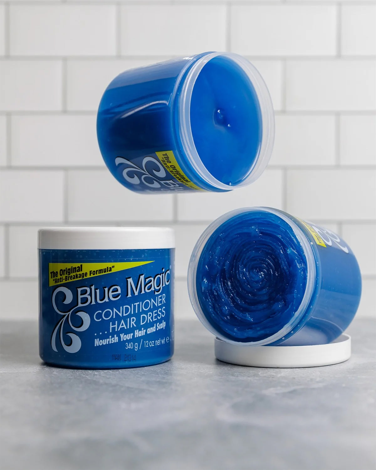 Three buckets of Blue Magic Conditioner Hair Dress. One closed, two open with the characteristic blue cream.