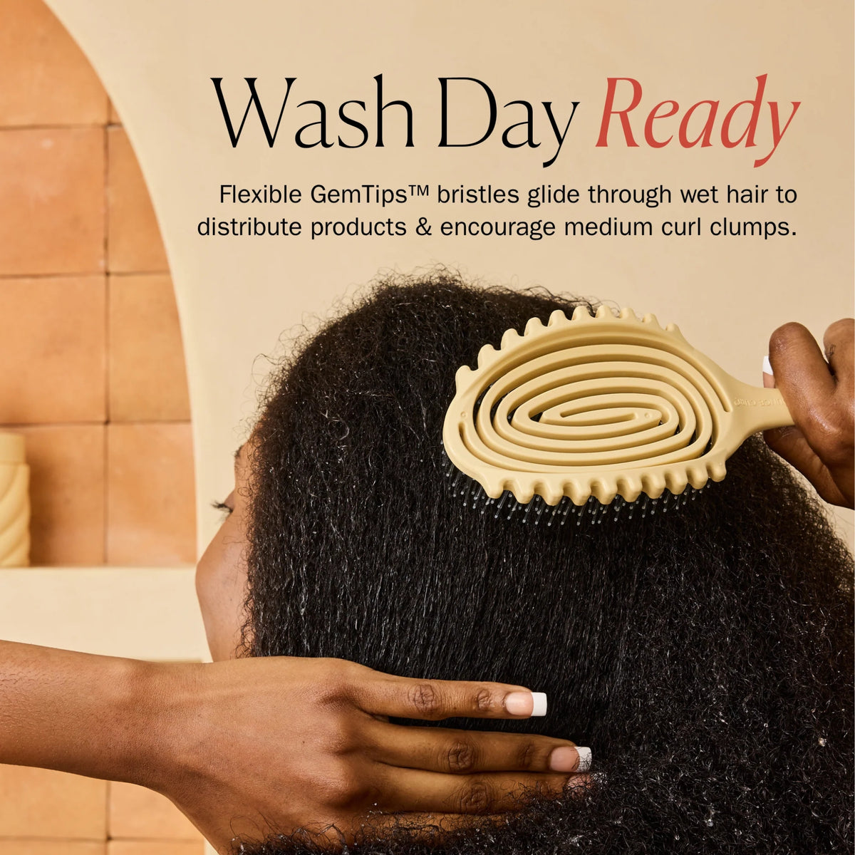 Yellow spiral hairbrush with GemTips bristles through wet afro hair during wash day routine.