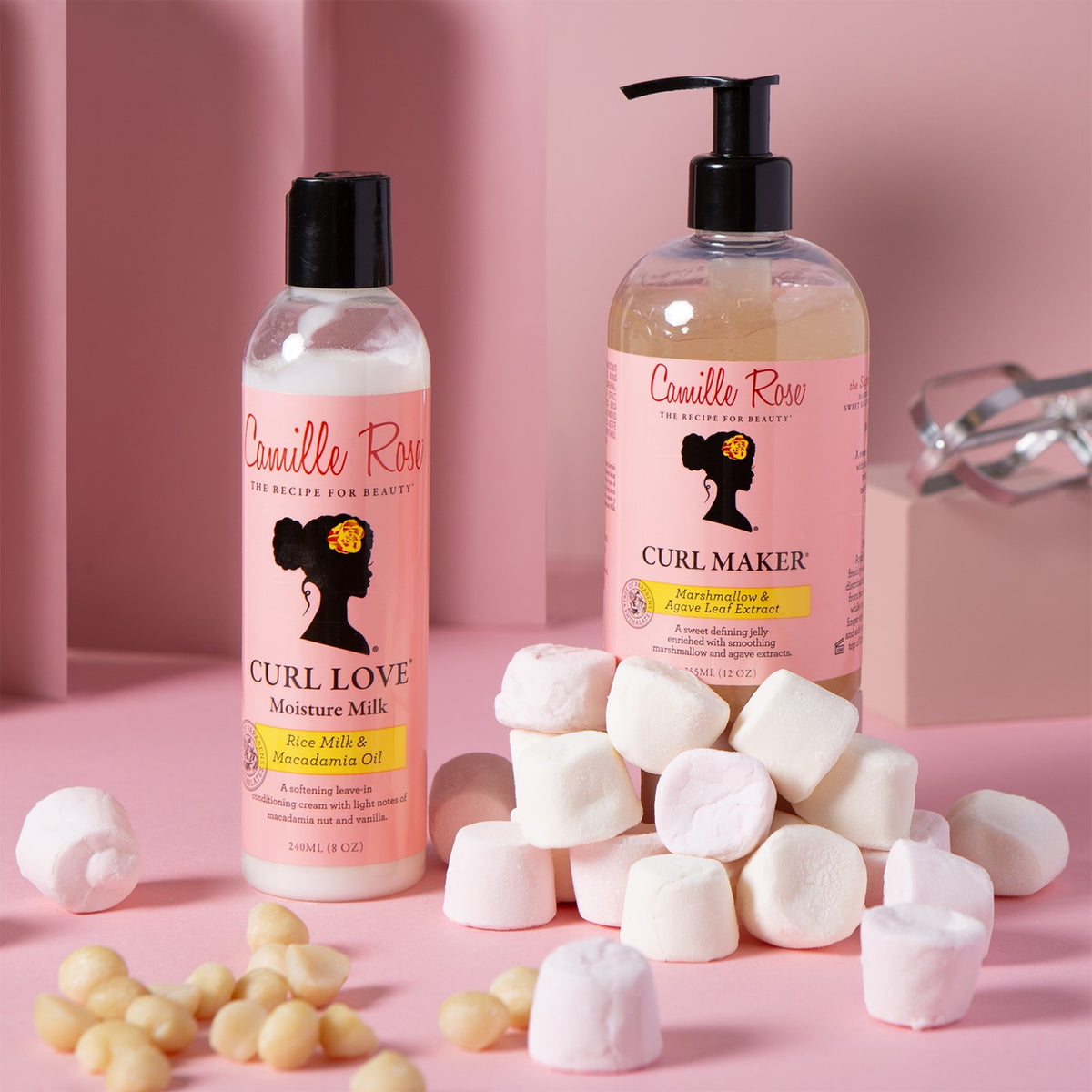 Camille Rose Curl Love Moisture Milk and Curl Maker in white/pink bottles with macadamia nuts and marshmallows.
