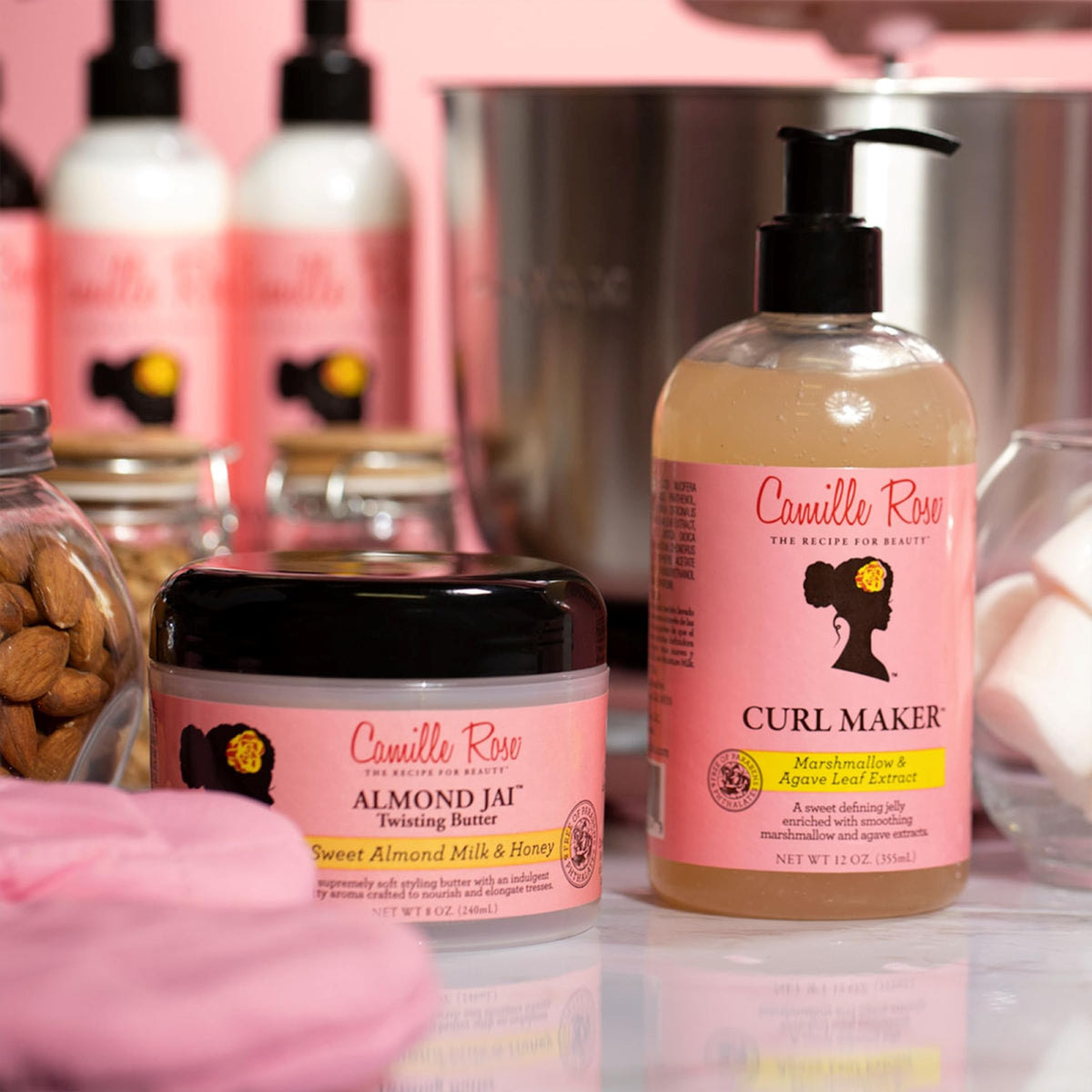 White plastic bottle with a black pump and pink cap containing Camille Rose Curl Maker hair product.