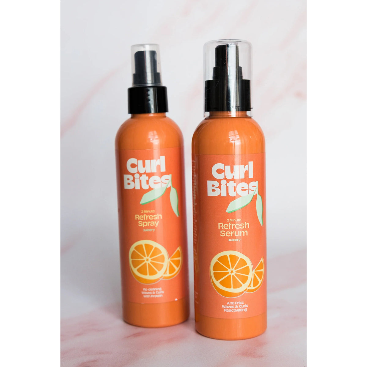Two orange Curl Bites bottles: 2 Minute Refresh Spray and Refresh Serum with an orange motif on a pink background.