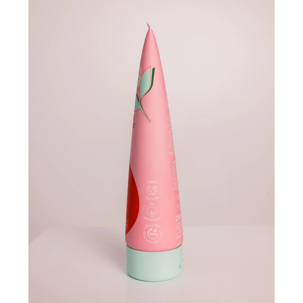 Pink tube hair shampoo with mint green lid, labeled with vegan and recyclable icons.