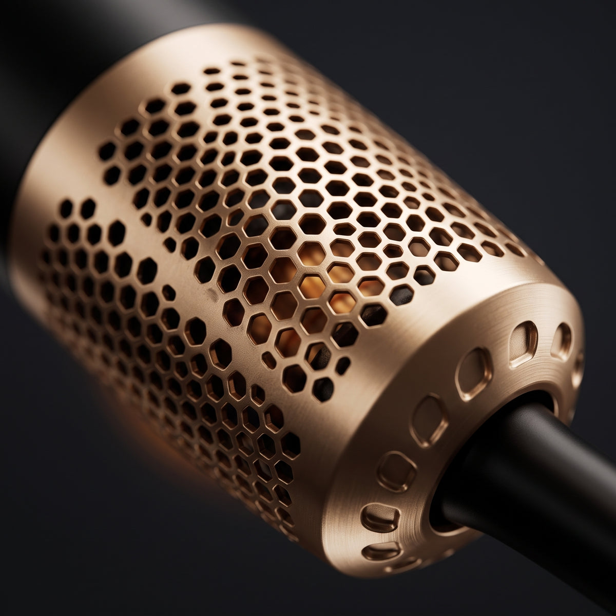 Bronze-colored microphone grille with hexagonal hole pattern in close-up against a black background.