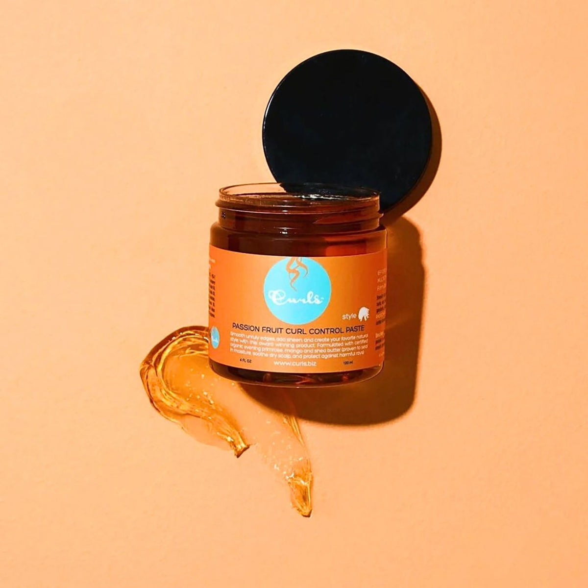 Curls Passion Fruit Curl Control Paste (120 ml) in an open jar on an orange background with passion fruit. Styling paste for defined curls.