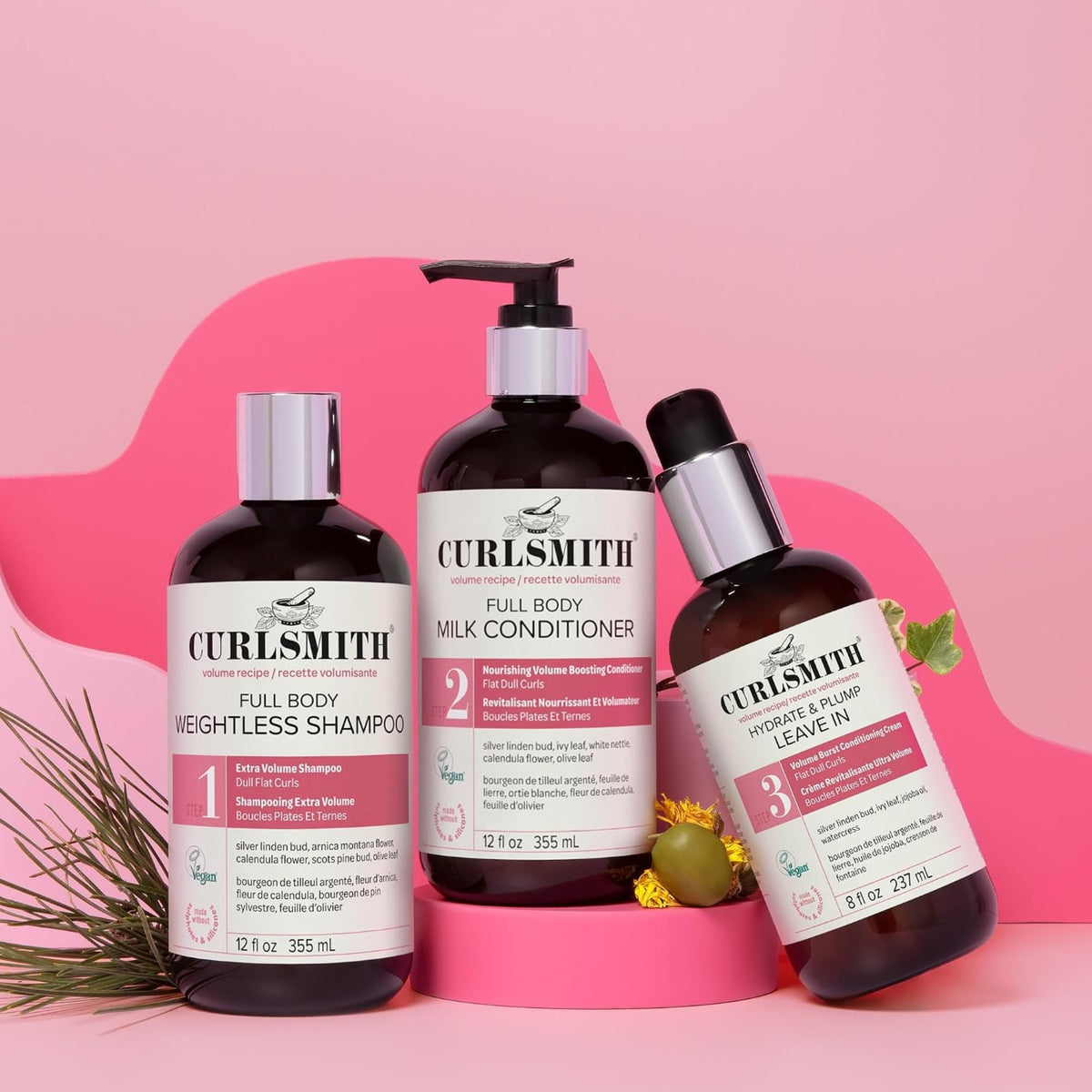 Curlsmith Full Body volume series: shampoo, milk conditioner and leave-in on a pink background with green leaves.