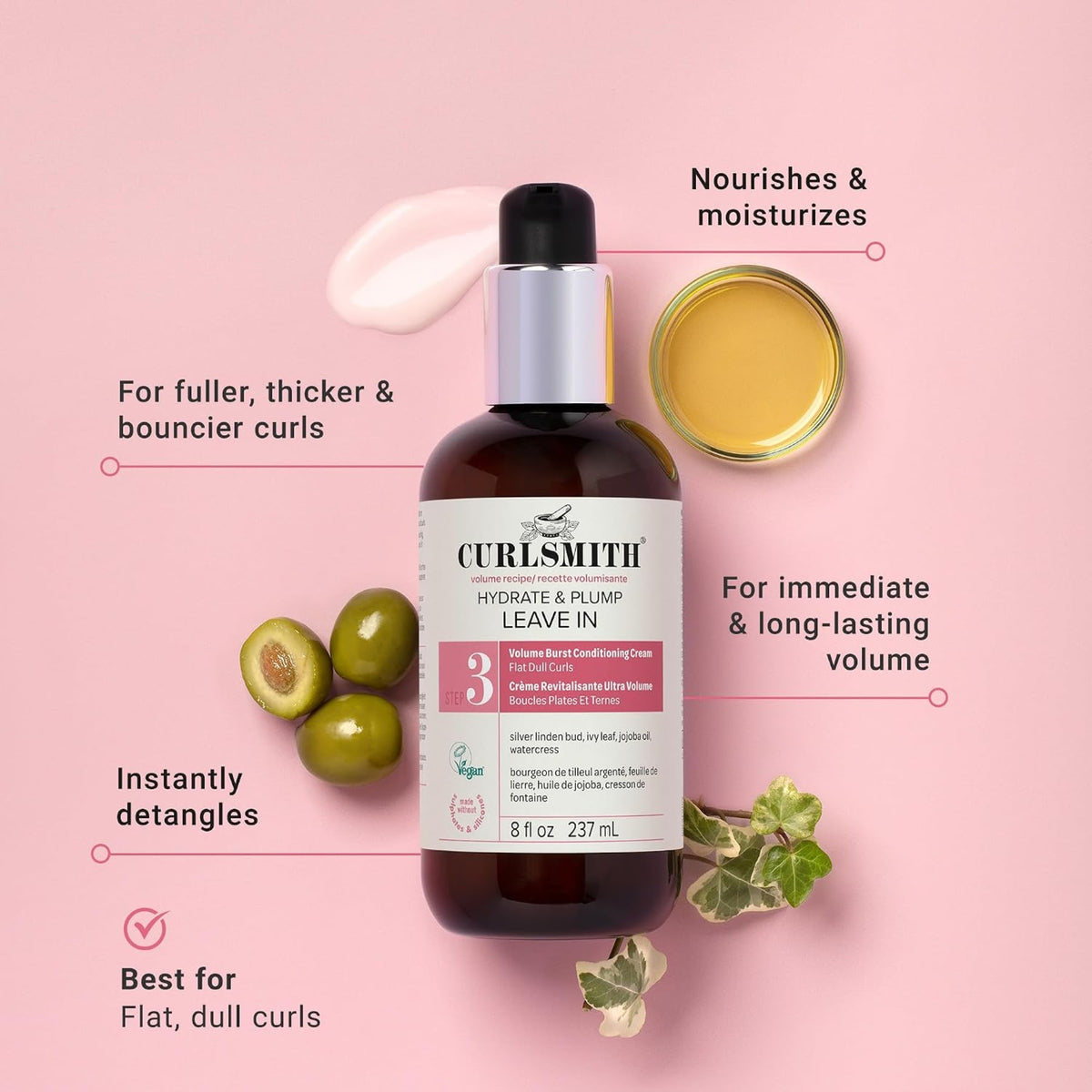 Curlsmith Hydrate & Plump Leave In bottle with olives, ivy leaves and golden oil on pink background.