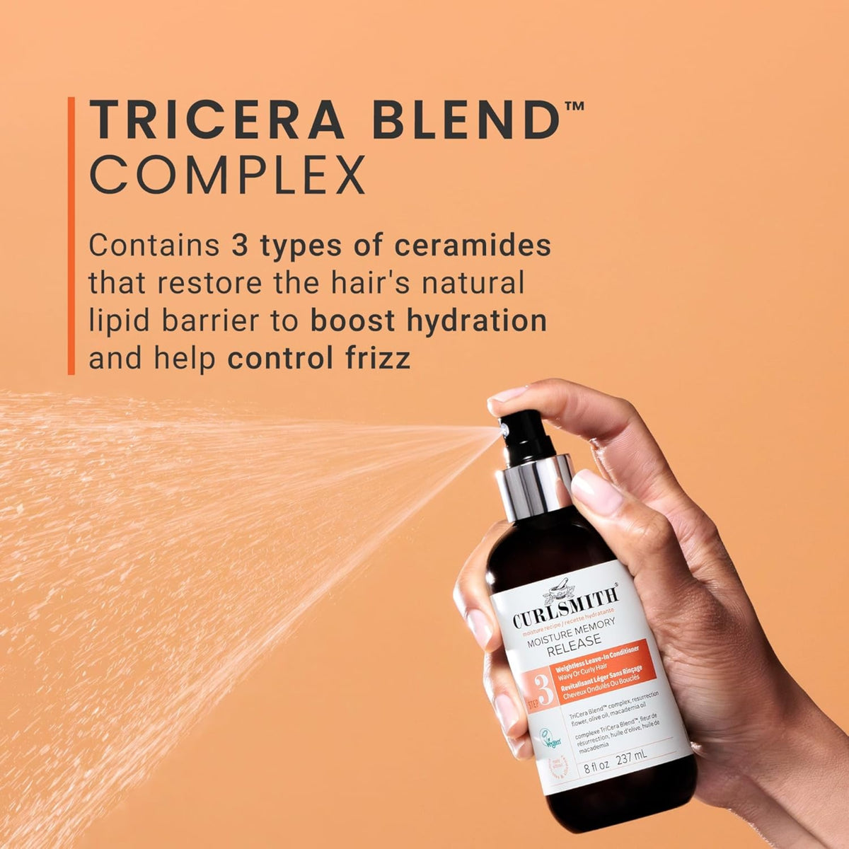 Hand sprays Curlsmith Moisture Memory Release with TriCera Blend Complex on orange background.