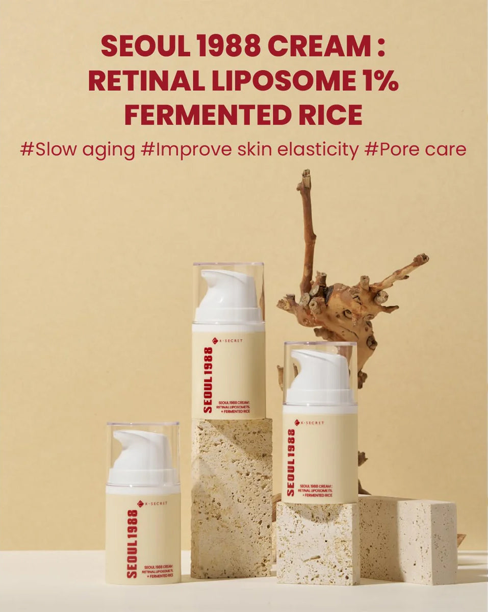 Three bottles of K-Secret Cream: Retinal Liposome 1% + Fermented Rice 50 ml stand on light stones in front of a beige background.