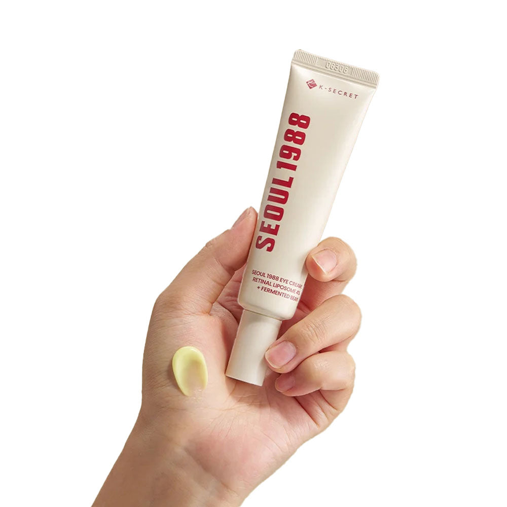 K-Secret Eye Cream: Retinal Liposome 4% + Fermented Bean 30 ml held in hand with yellow creamy consistency on the skin.