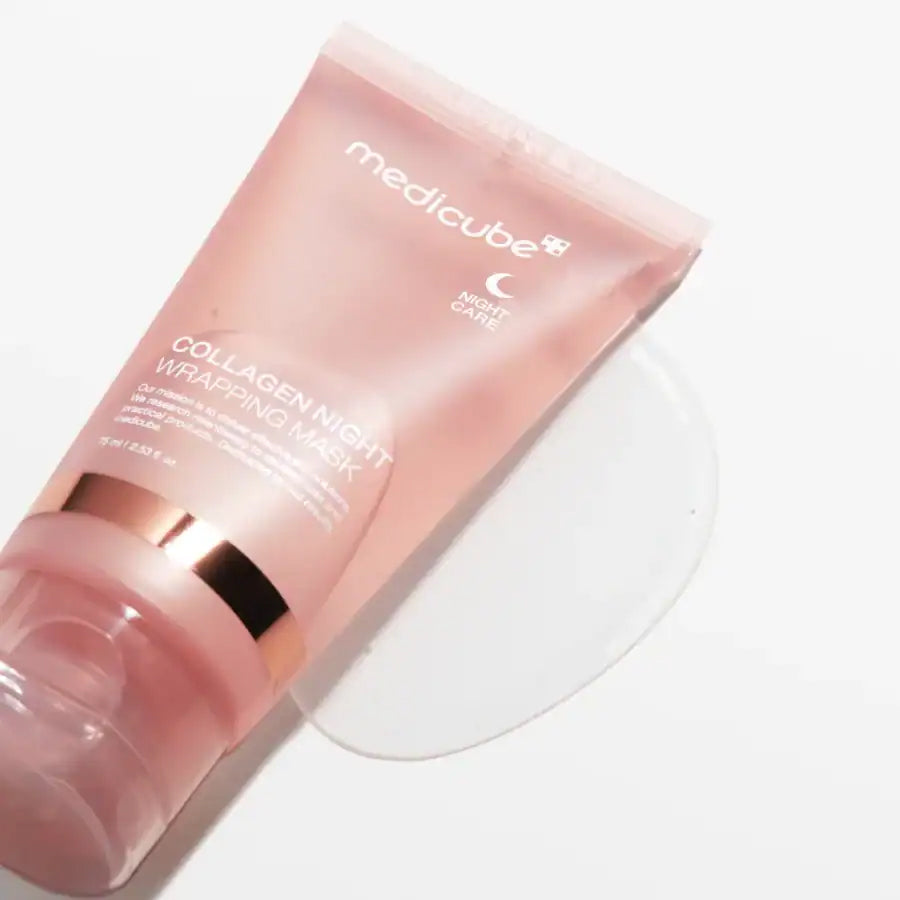 Medicube Collagen Night Wrapping Mask 75ml in pink tube lies on a white background with a little gel around the opening.