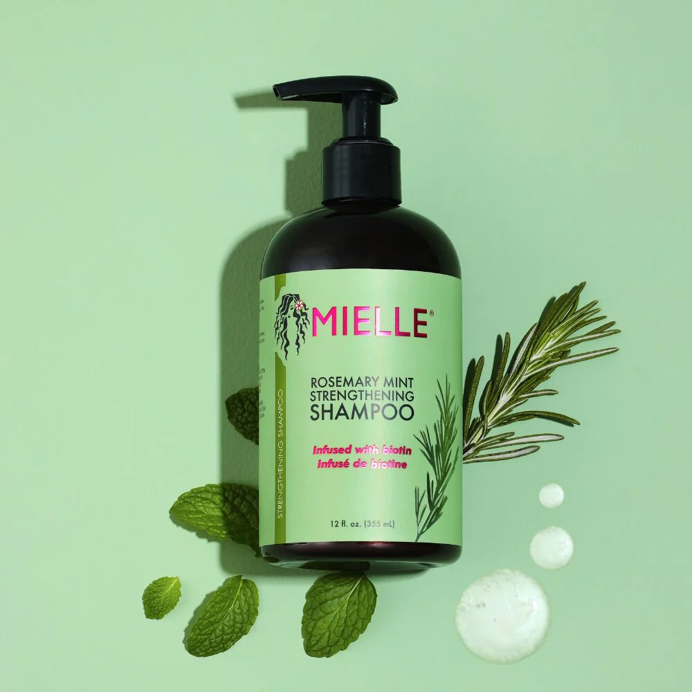 Bottle of Mielle Rosemary Mint Strengthening Shampoo (355 ml) with black pump, green label, rosemary, mint leaves and light green background.
