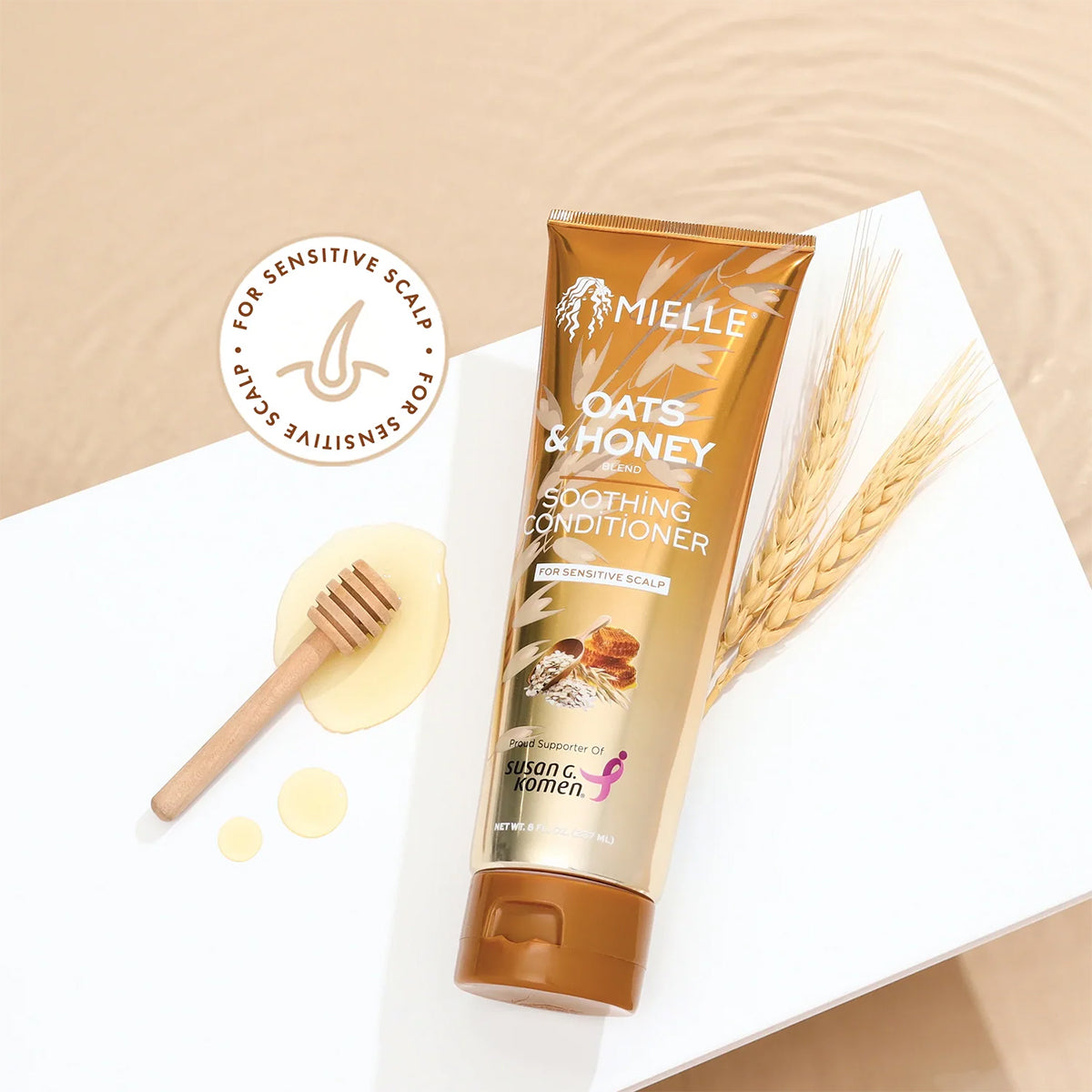 Mielle Oats & Honey Soothing Conditioner 237ml with spoonful of honey and oat straw on white surface at water level.