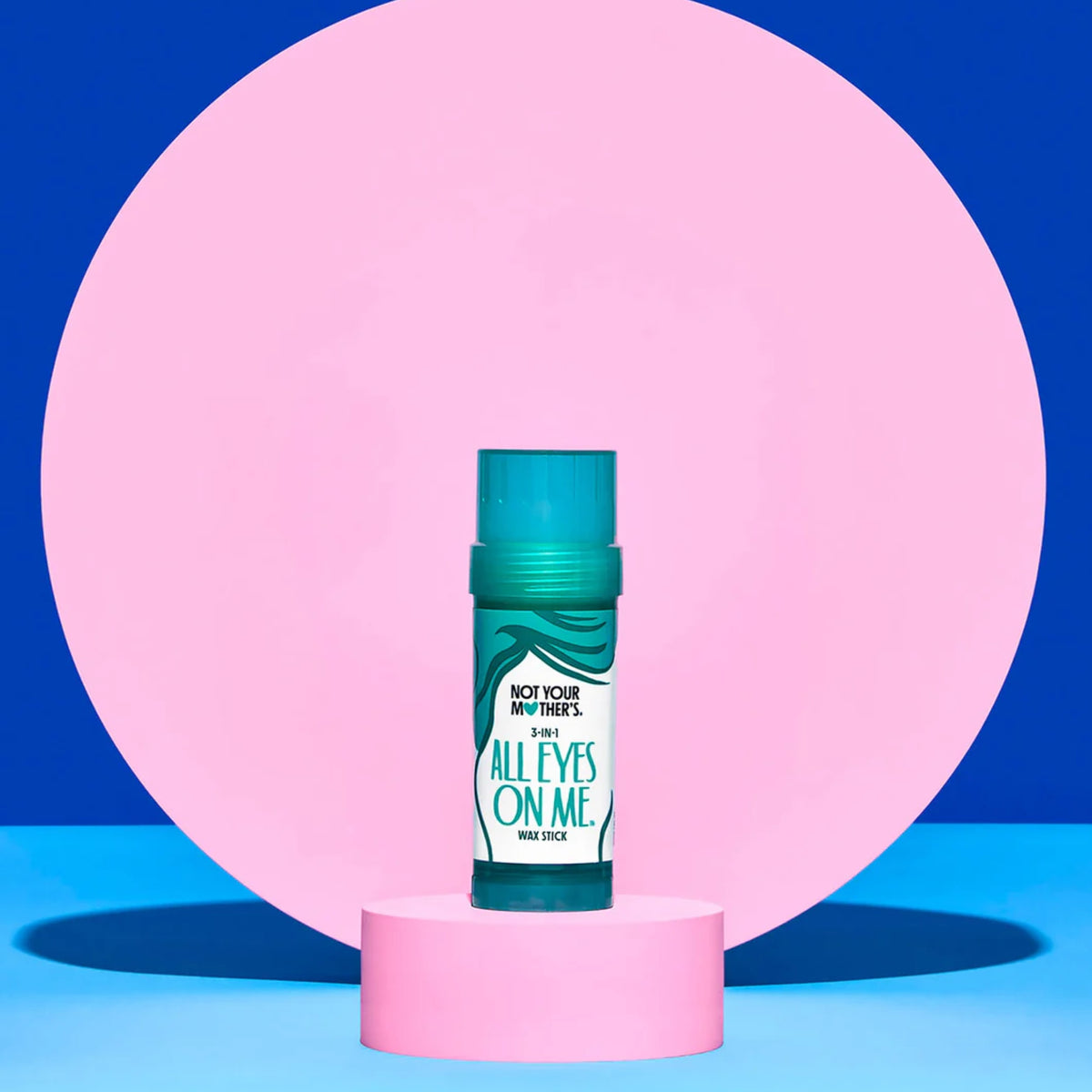 Not Your Mother's All Eyes On Me 3-in-1 wax stick in turquoise on pink podium against blue background.