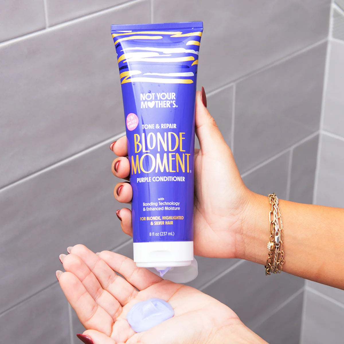 Not Your Mother's Blonde Moment purple conditioner in one hand with a dollop of product in the other.