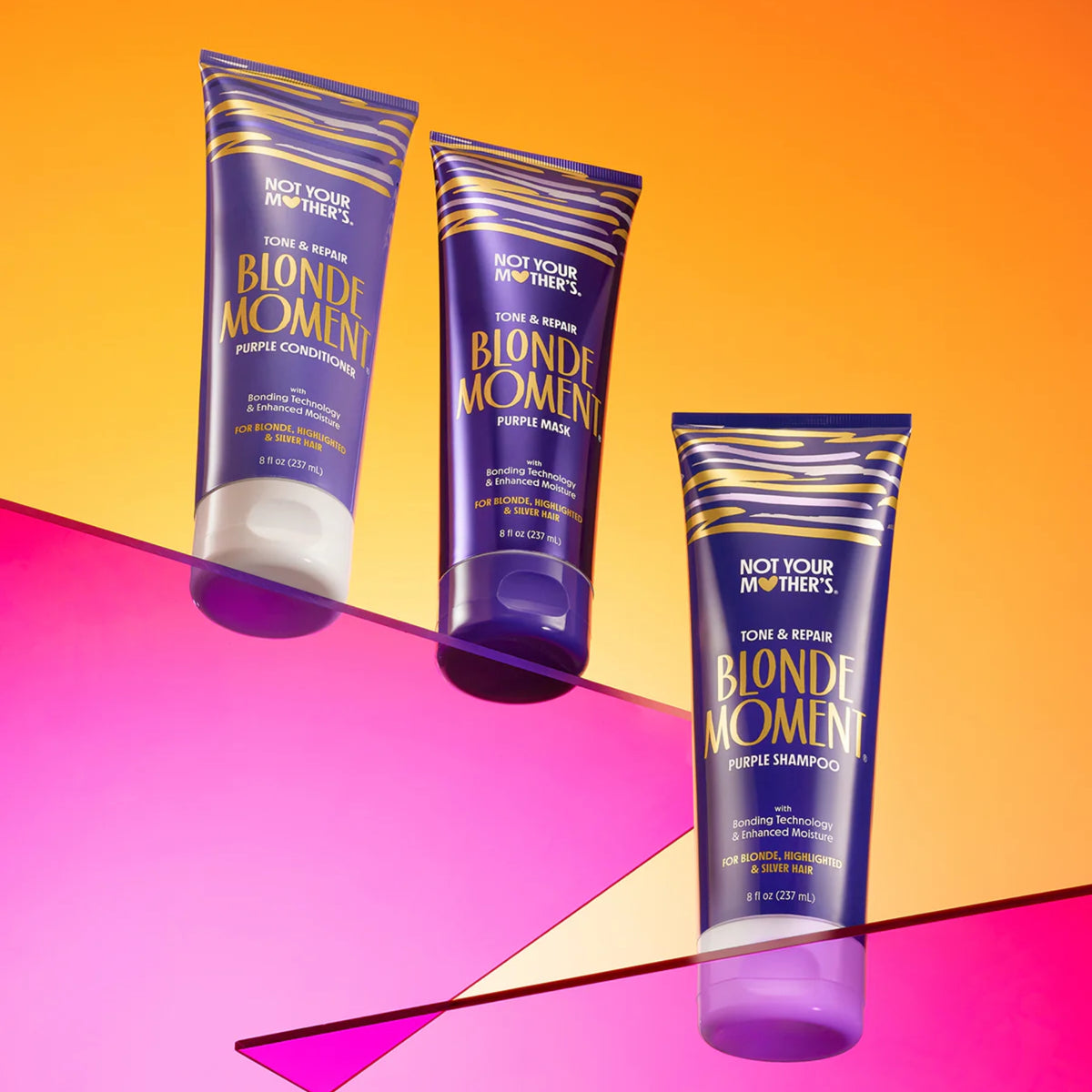 Not Your Mother's Blonde Moment purple shampoo, conditioner and mask against a colorful orange and pink background.