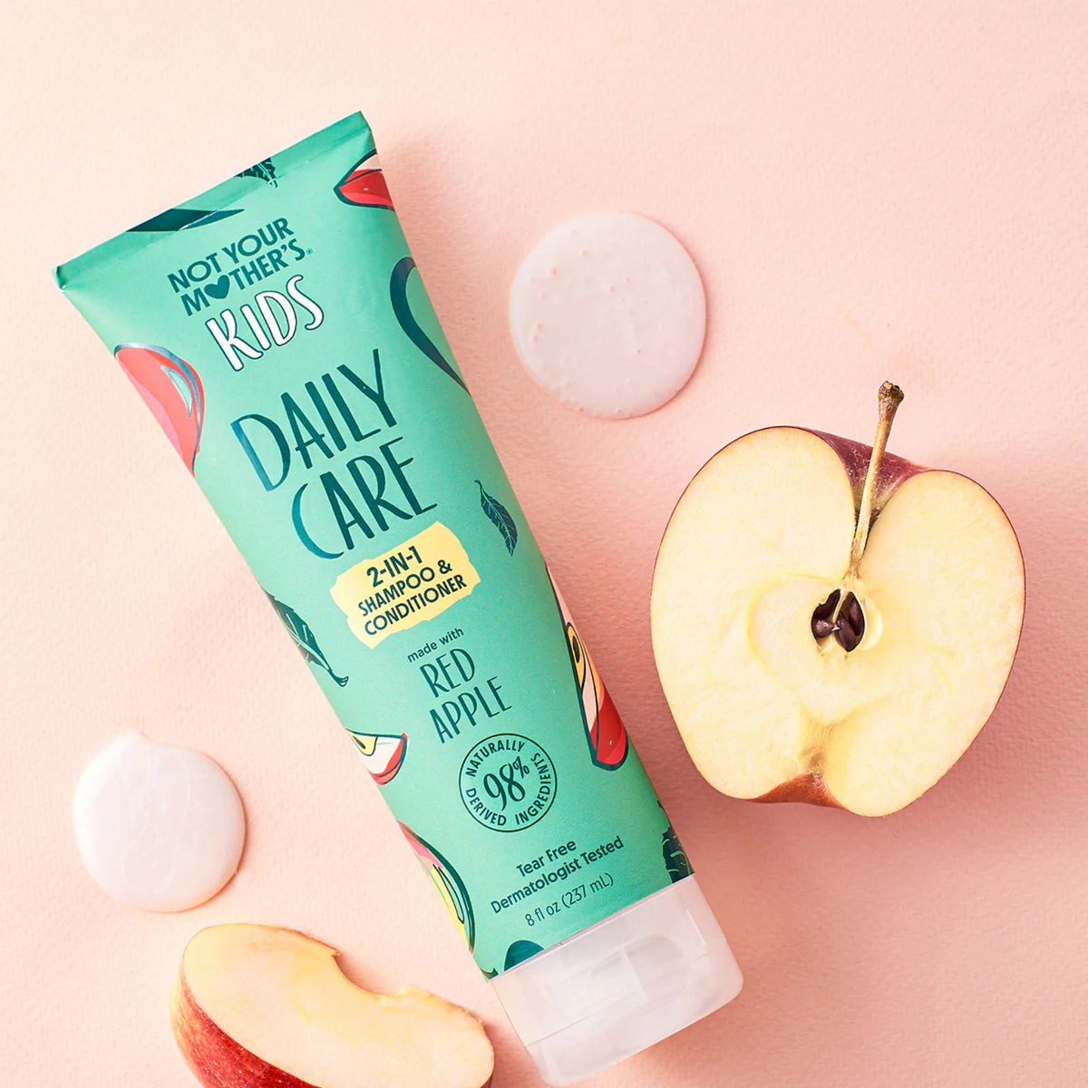 Not Your Mother's Kids Daily Care 2-in-1 shampoo and conditioner with red apple next to fresh apple slices.
