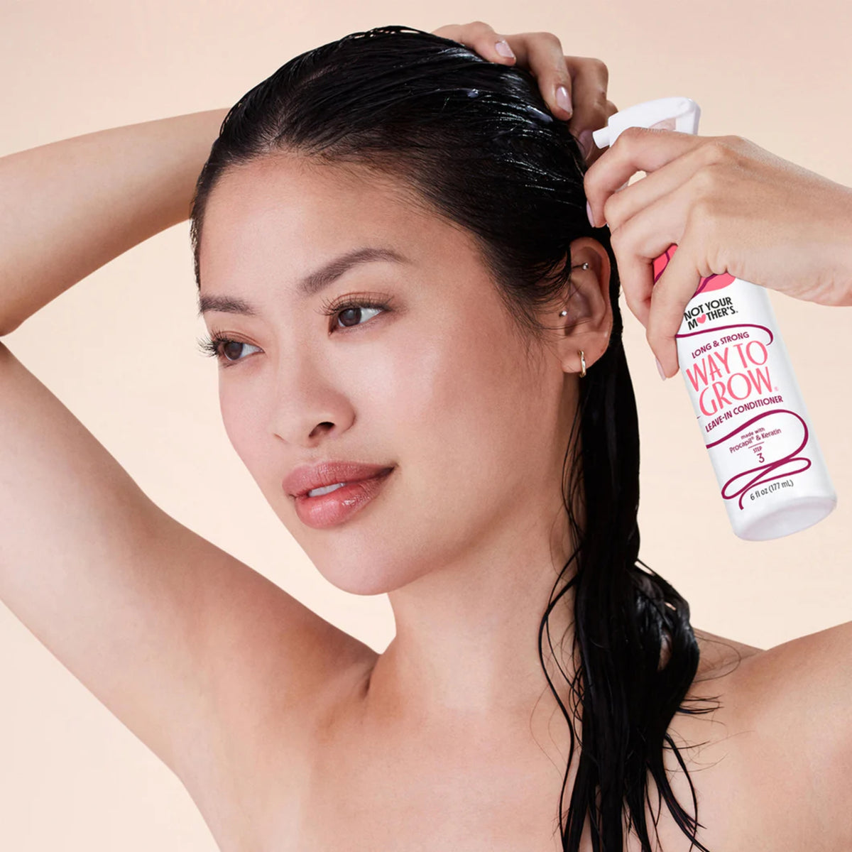 Woman with wet hair sprays Not Your Mother's Way To Grow leave-in conditioner into her hair.