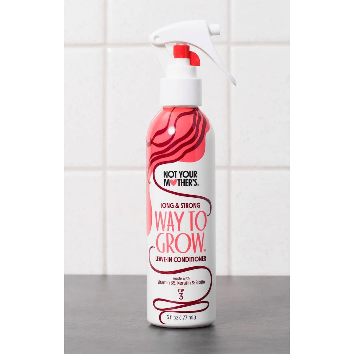 Not Your Mother's Way to Grow leave-in conditioner in spray bottle with red pattern on kitchen table.