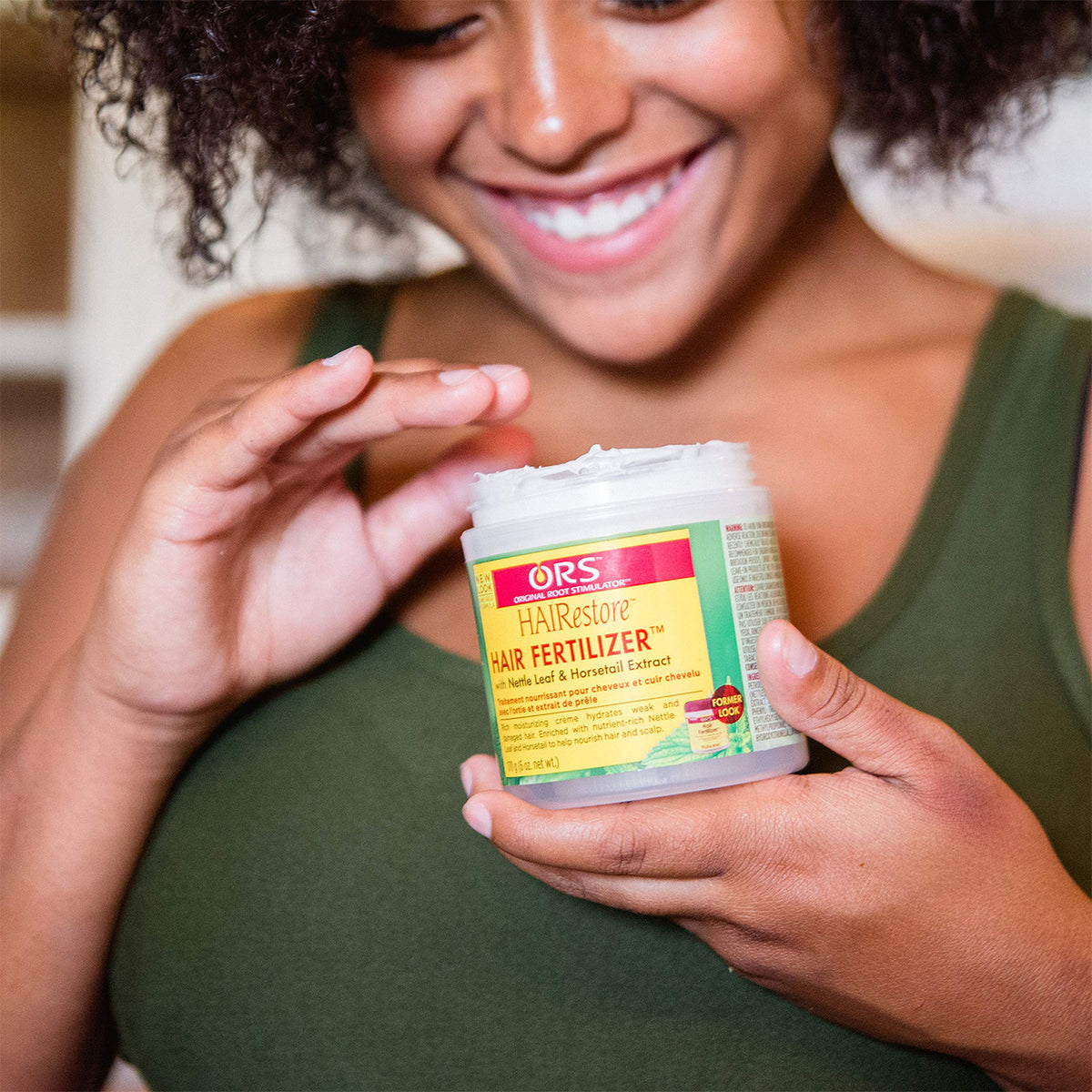 Woman holding ORS HAIRestore Hair Fertilizer (170g) which contains nettle and horsetail.