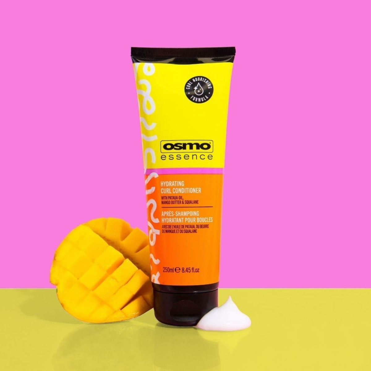 Osmo Essence Hydrating Curl Conditioner tube in yellow and orange with carved mango on a pink background.