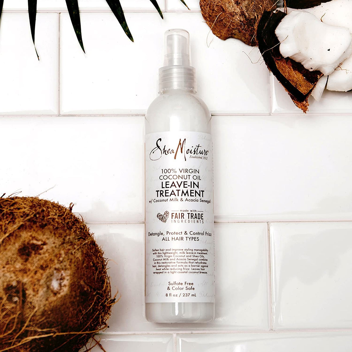 A spray bottle with a white label. The product is Shea Moisture 100% Virgin Coconut Oil Daily Hydration Leave-In Treatment, 237ml. Leave-in conditioner to detangle and reduce frizz in the hair.