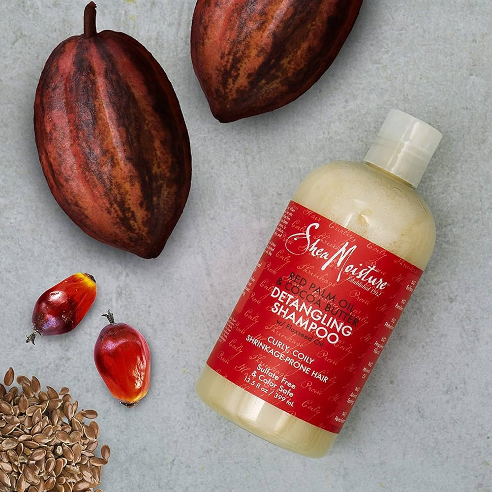 Shea Moisture Red Palm Oil & Cocoa Butter Hi-Slip Detangling Shampoo 399ml. The image shows the shampoo together with raw ingredients: cocoa beans, red palm oil and linseed.