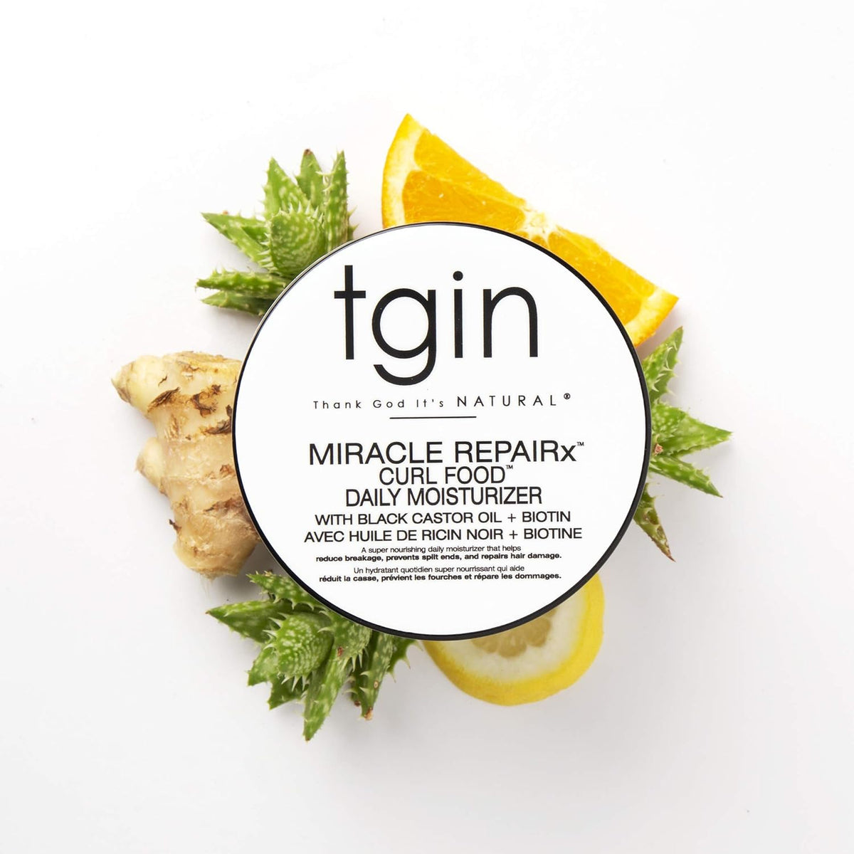 TGIN Miracle RepairX Curl Food 340gr surrounded by aloe vera, ginger, lemon slice and orange on a white background.