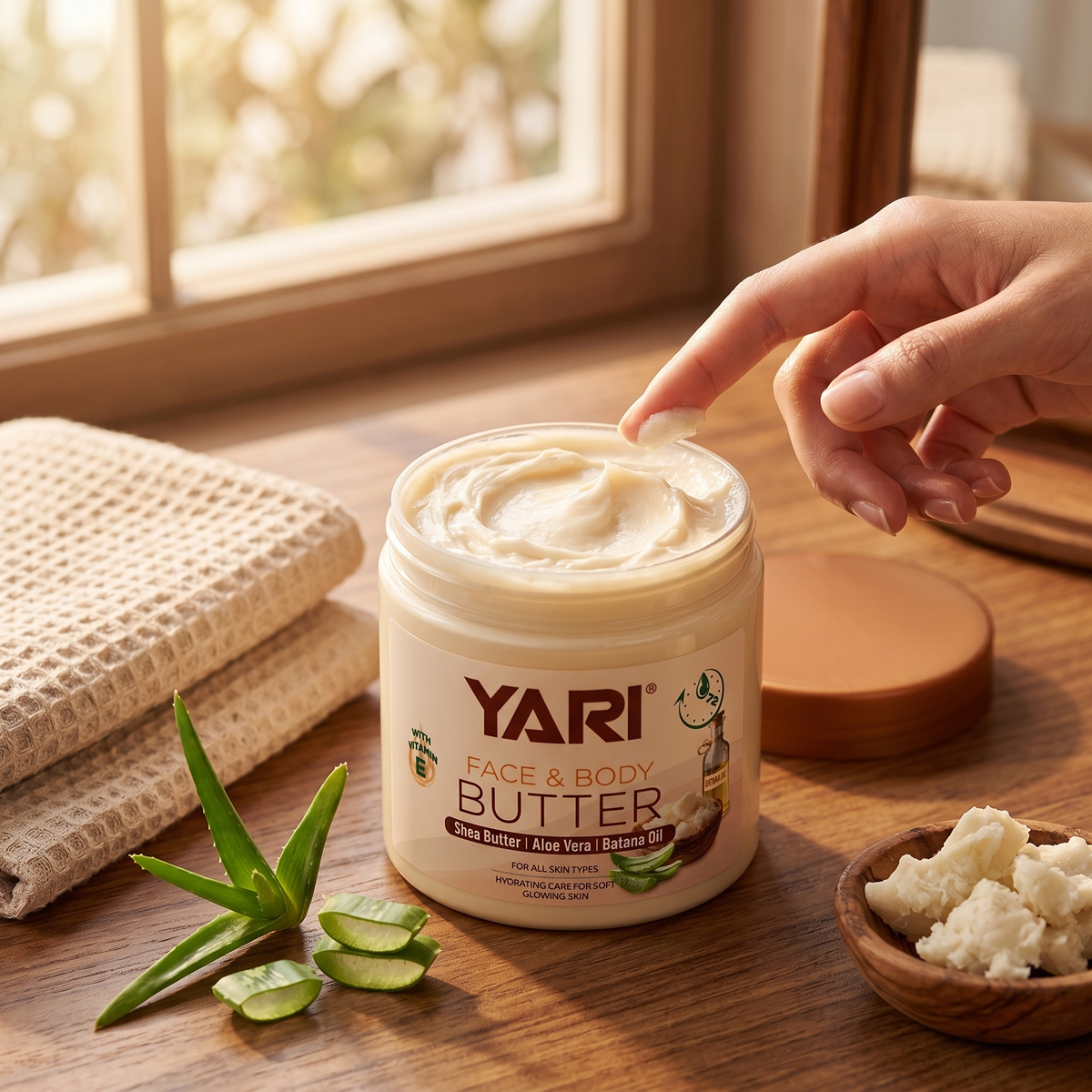 Yari Face & Body Butter with shea, aloe vera and batana oil on wooden table with finger taking cream.